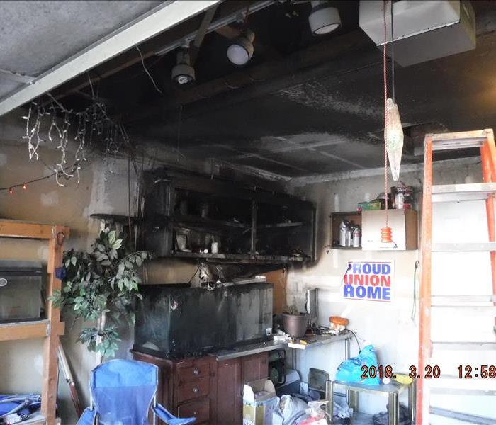 Black walls, ceiling, and cabinet from fire and smoke in a garage.