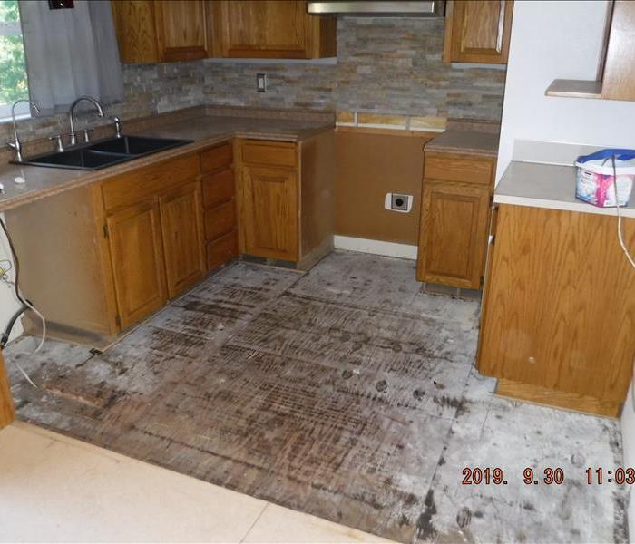 Wet flooring cut out, exposed dry sub floor in kitchen space