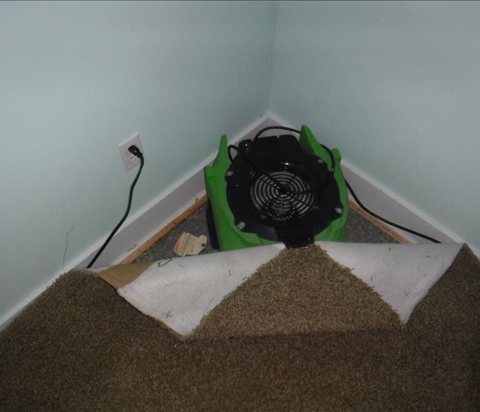 Fan in a corner with a piece of green equipment